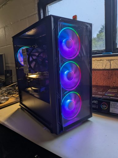 Black computer case with three illuminated RGB fans in front.