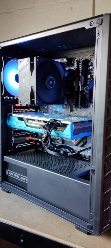 A gaming PC with LED lights showcasing internal components and a cooling fan.