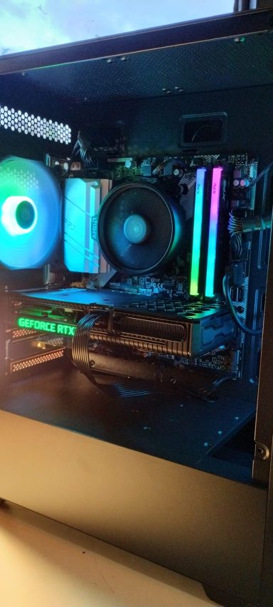 A computer interior showing RGB lighting, cooling fans, and hardware components.