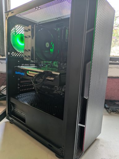A sleek black computer case with a green fan and visible interior components.