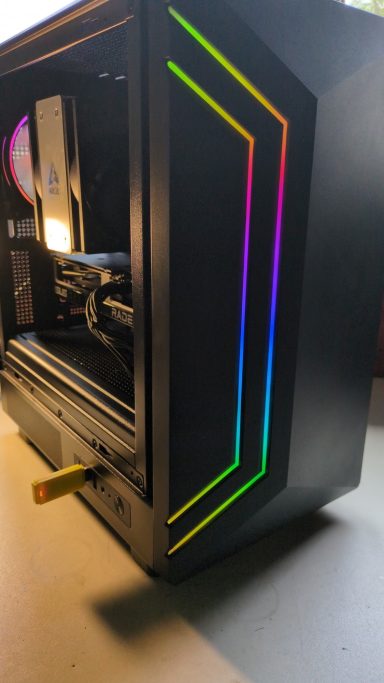 Black computer case with colourful LED strips and an open side panel.